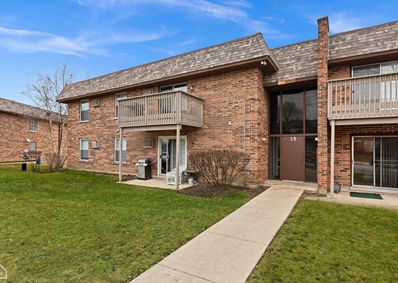 a brick apartment building with a sidewalk in front of it