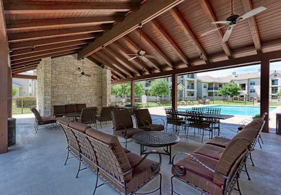 A patio with a table and chairs and a pool in the background.