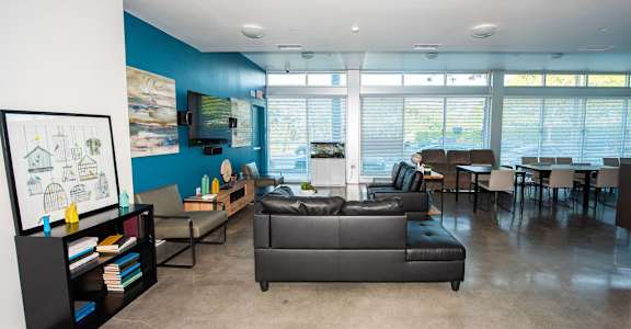 A living room with a grey couch and a bookshelf.