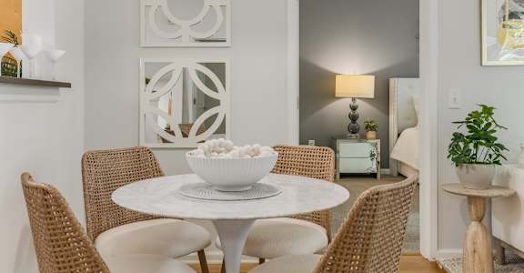 A white bowl is on a white table with four chairs around it.