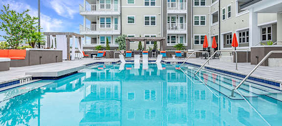 A large swimming pool in front of a multi-story apartment building.