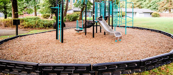 A playground with a slide, swings, and a teeter-totter.