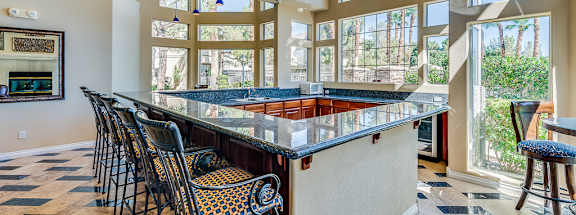 A kitchen with a long bar and chairs.