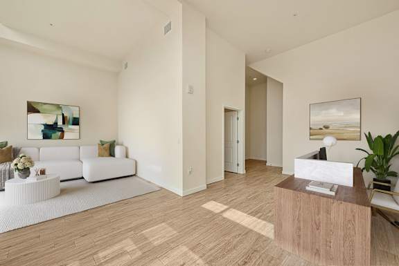 A spacious living room with a white sofa and a wooden coffee table.