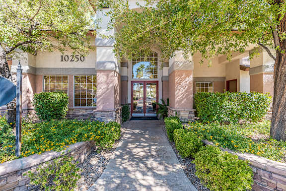 a walkway to a building with trees and bushes