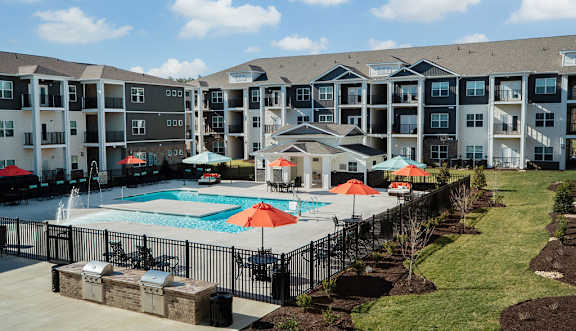 A large apartment complex with a pool and umbrellas.