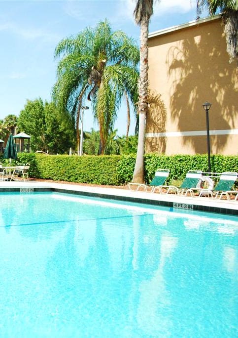 a swimming pool in front of a hotel with palm trees at Hidden Cove, Miami Florida