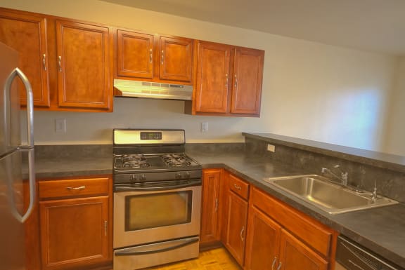 Kitchen with stainless steel appliances, wooden cabinets and grey/blue counter tops