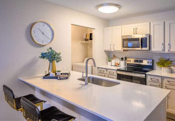 A kitchen with a white countertop and a clock on the wall.