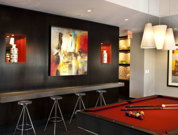 Pool table with bar seating. Wood accent wall with orange painting and accents