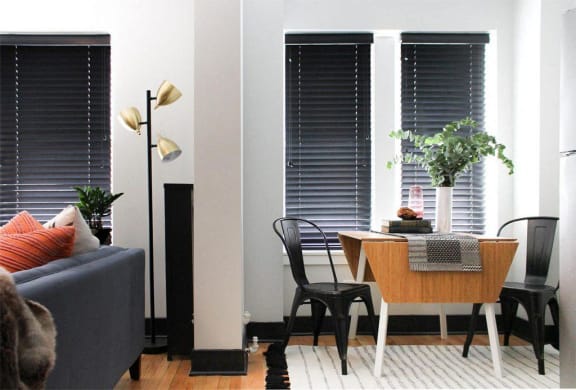 a dining room with a table and chairs and windows with blinds