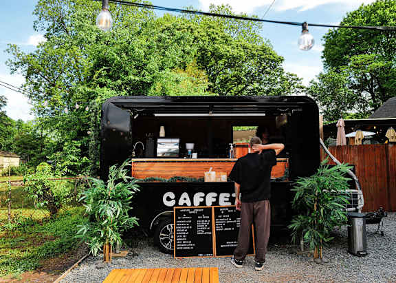 A man is standing outside a coffee truck.