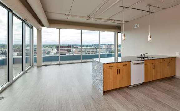 A modern kitchen with wooden cabinets and a large window overlooking the city.at City Square Lofts, Des Moines, IA 50309
