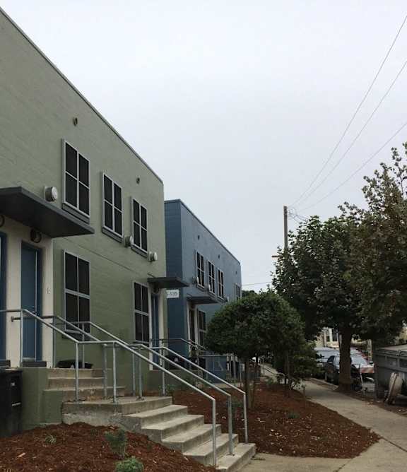 A grey building with a blue door and windows.
