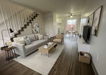 A living room with a grey couch and a wooden floor.