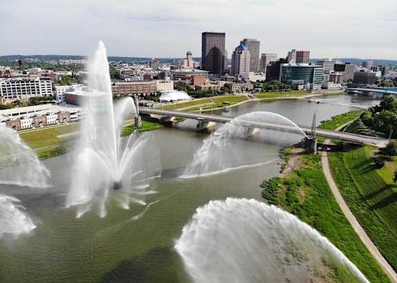 A fountain in the foreground with a city skyline in the background.