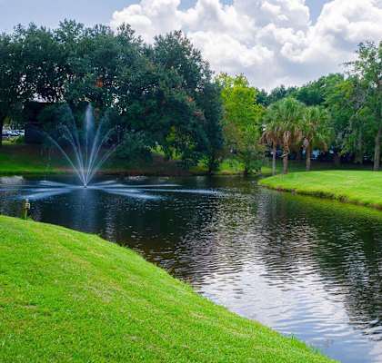 A fountain in the middle of a pond surrounded by trees.at Auburn Glen Apartments, Florida, 32256