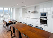 Thumbnail 9 of 16 - A modern kitchen with a wooden table and chairs.