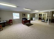 Thumbnail 10 of 24 - A room with a desk, chairs, and a framed picture on the wall.