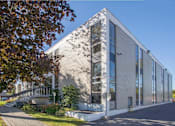 Thumbnail 7 of 7 - A modern building with a grey facade and large windows.