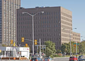 Thumbnail 8 of 9 - A large building with a lot of windows is in the background of a busy street.