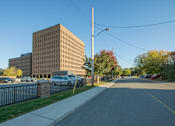 Thumbnail 1 of 9 - A street view with a building, cars, and trees.