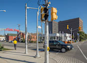 Thumbnail 5 of 9 - A pedestrian is walking on a sidewalk next to a traffic light.