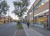 Thumbnail 6 of 6 - A woman is walking down a sidewalk past a Belty Brite store.