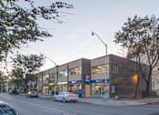 Thumbnail 3 of 6 - A street view of a building with cars parked in front of it.