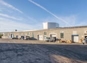 Thumbnail 2 of 6 - A large industrial building with a clear blue sky above.