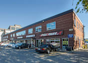 Thumbnail 1 of 6 - A building with a red brick facade has a sign that says "CYCLE POWER" on it.