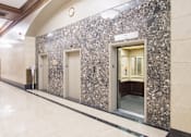 Thumbnail 3 of 7 - A hallway with a marble wall and a white door.