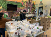 Thumbnail 3 of 13 - Mutual Housing staff fill grocery bags in the Spring Lake community room
