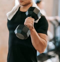 A man in a black shirt is lifting a dumbbell in a gym.