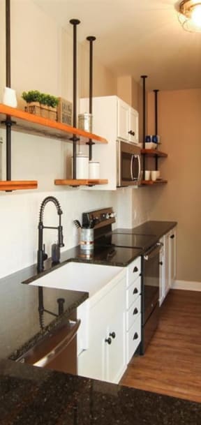 a kitchen with white cabinets and black counter tops