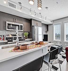 A modern kitchen with a red couch and black chairs.