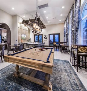 a pool table in a clubhouse with a bar and tables