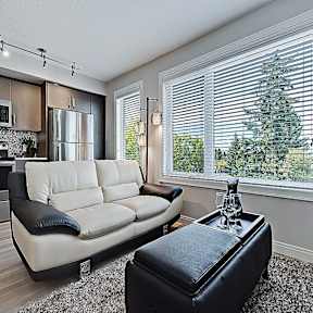 A modern kitchen with a white couch and a black ottoman.