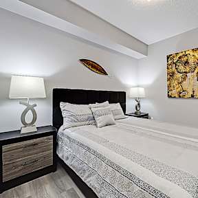 A bedroom with a bed, nightstand, and a painting on the wall.