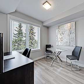 A room with a desk, chairs, and a painting on the wall.