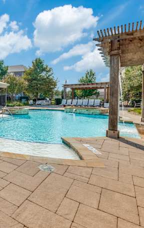 A large outdoor swimming pool surrounded by a tiled patio area.