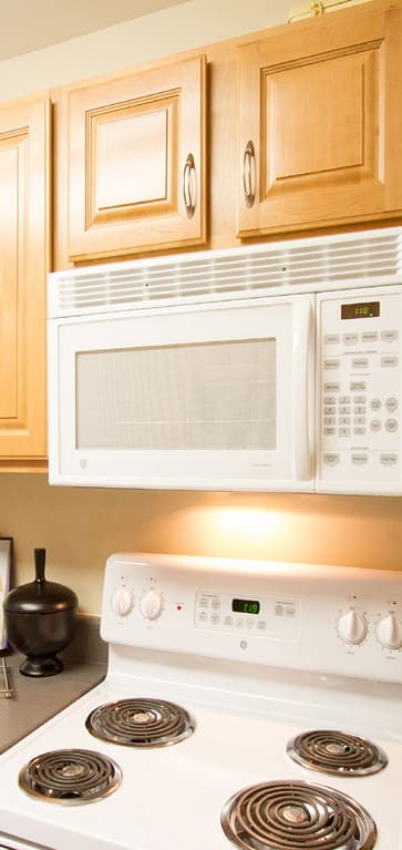 a kitchen with white appliances and wooden cabinets at The Summit at Owings Mills Apartments, Owings Mills, MD 21117