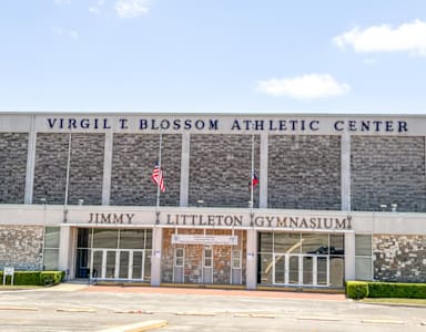 A large building with a sign that says "Virgil T Blossom Athletic Center Jimmy Littleton Gymnasium.".