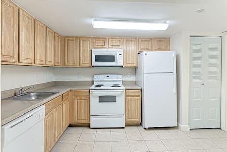 A kitchen with white appliances and wooden cabinets.