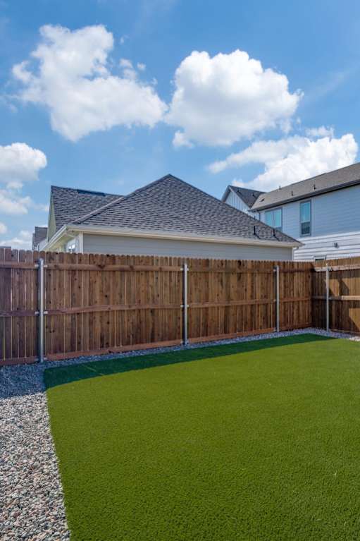 A backyard with a green lawn and a wooden fence.