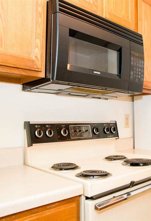 A black microwave oven is mounted above a white stove.
