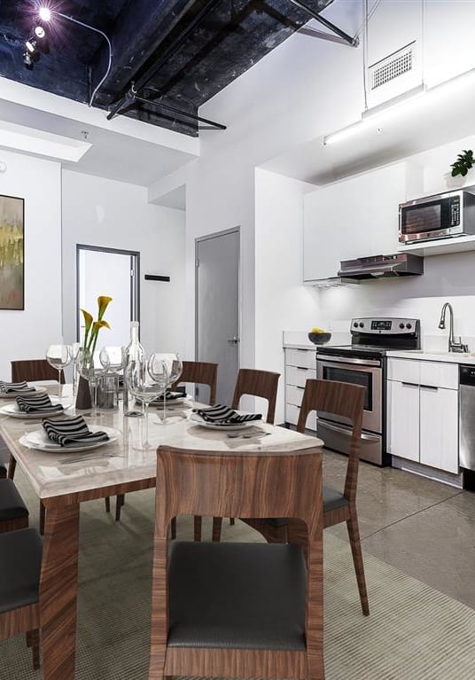 a dining room with a table and chairs and a kitchen in the background