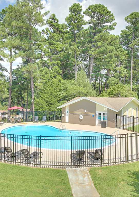 A pool surrounded by a black fence with a house in the background.