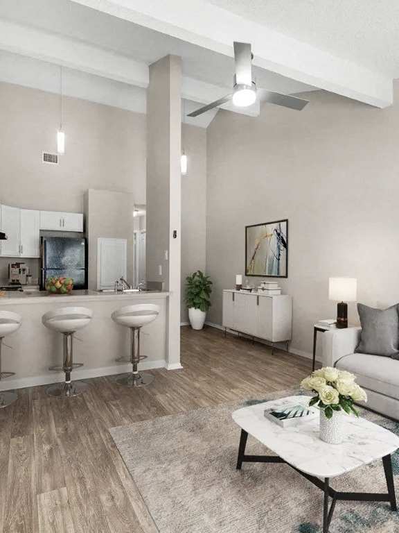 A living room with a white couch, a coffee table, and a bar area with stools.