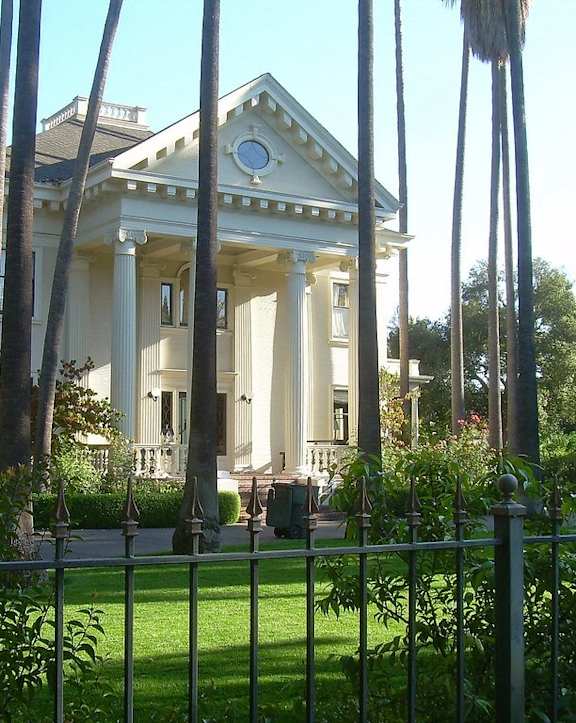 a large white house with columns in front of a fence